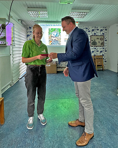 Ein Mann überreicht unserer Tierärztin eine Spende