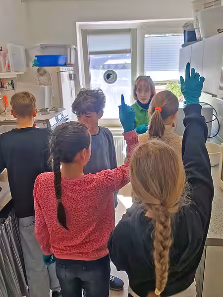 Unsere Mitarbeiterin steht mit den Kindern in unserer Futterküche, zwei Kinder melden sich.