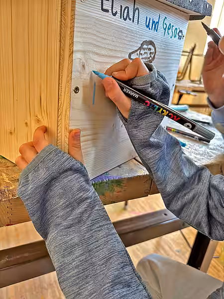 Kinderhände malen mit Stiften auf dem Igelhaus.