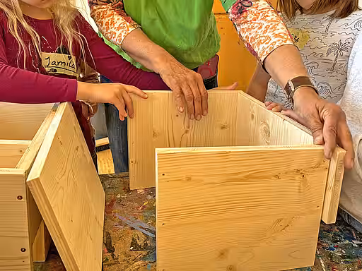 Kinder und Mitarbeiterin beim Bau eines Igelhauses.
